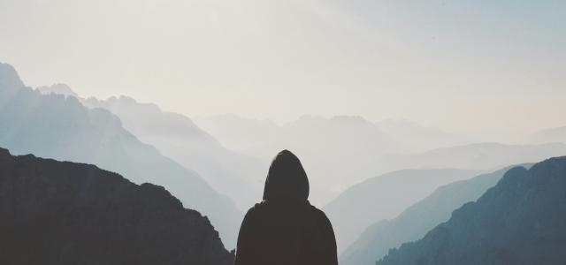 man in hoodie standing in front of the mountain by Matt Sclarandis courtesy of Unsplash.