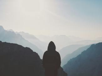 man in hoodie standing in front of the mountain by Matt Sclarandis courtesy of Unsplash.