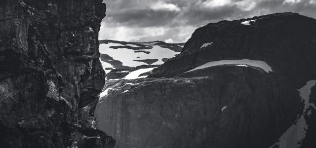 grayscale photo of rocky mountain under cloudy sky by Marek Piwnicki courtesy of Unsplash.
